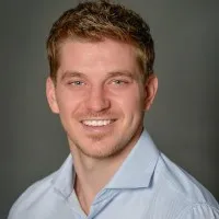 Smiling person wearing a blue shirt, professional portrait.