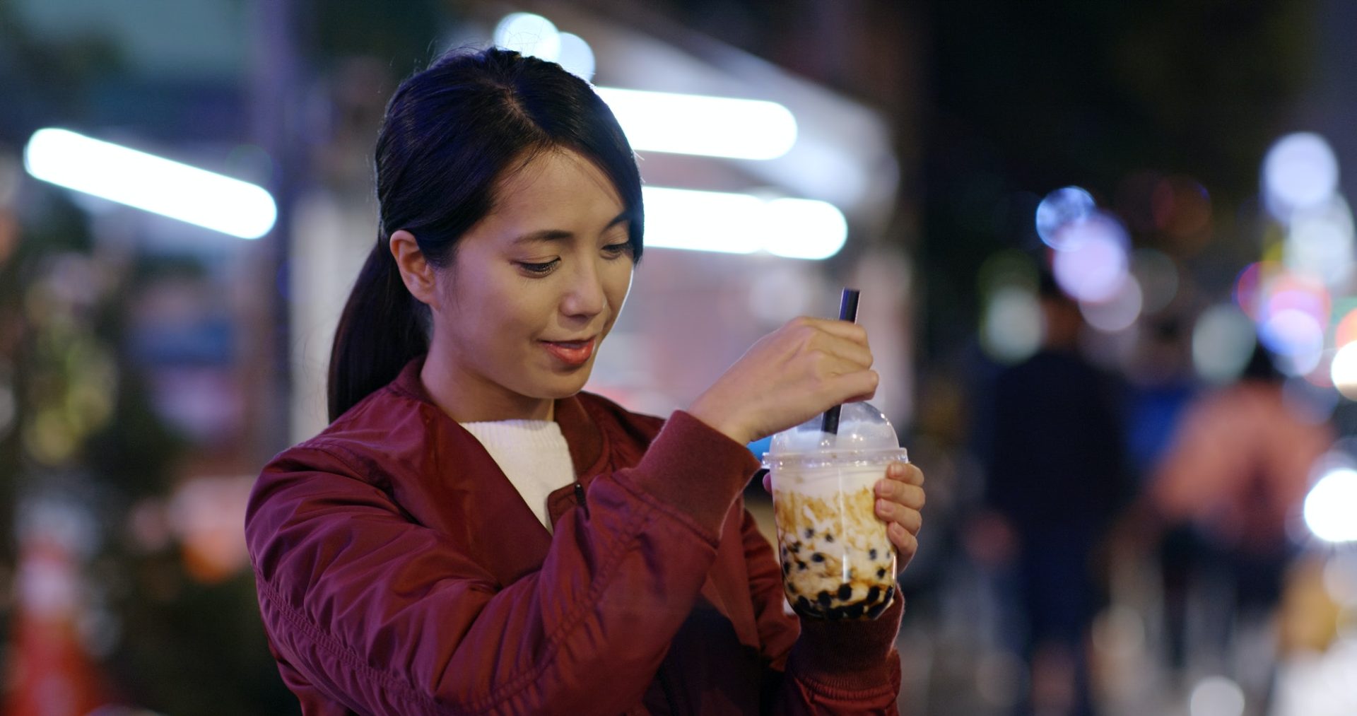 Woman enjoy iced bubble tea in city at night