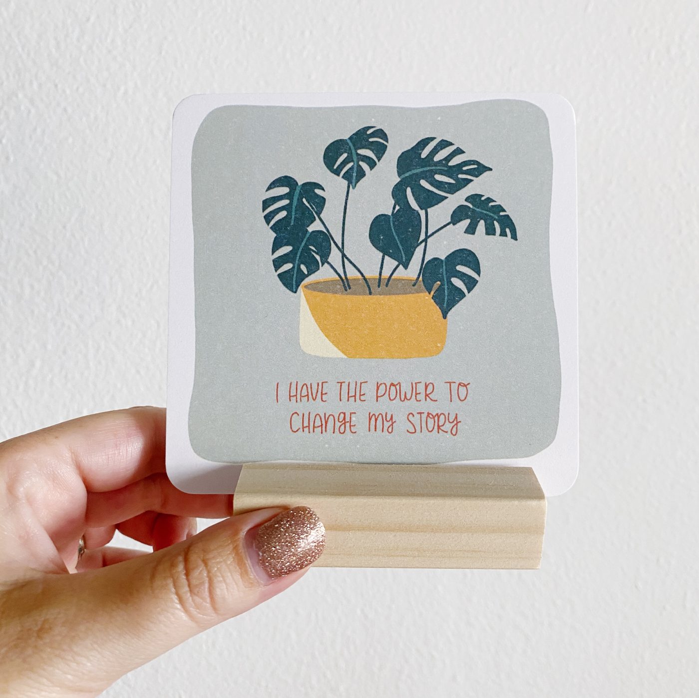 Hand holding motivational card with potted plant illustration