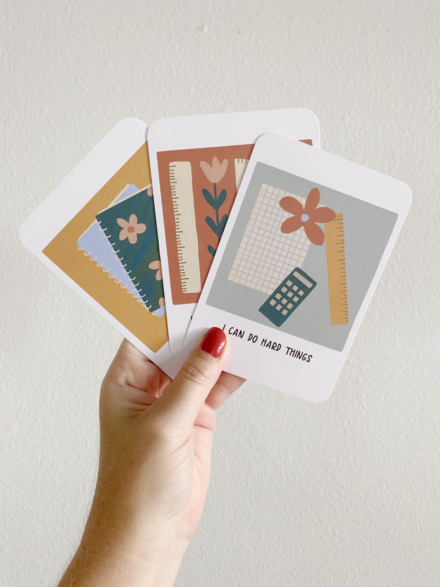 Hand holding three illustrated motivational cards