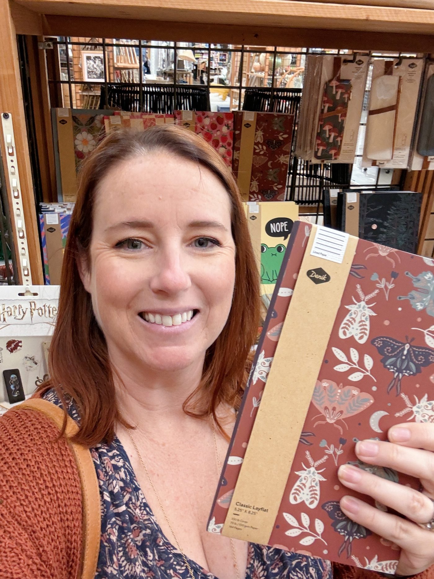 Woman holding decorative notebooks in a store