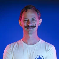 Man with mustache wearing white shirt against blue background