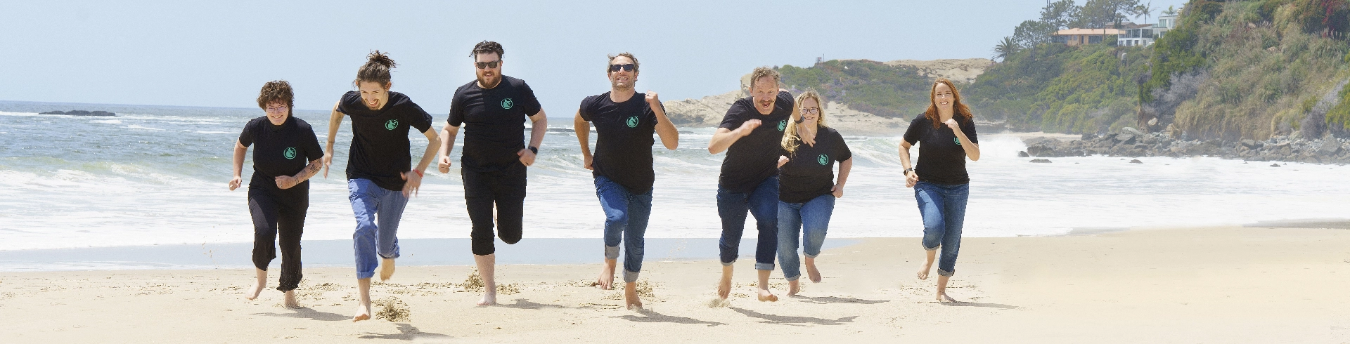 Group of people running on a beach together.