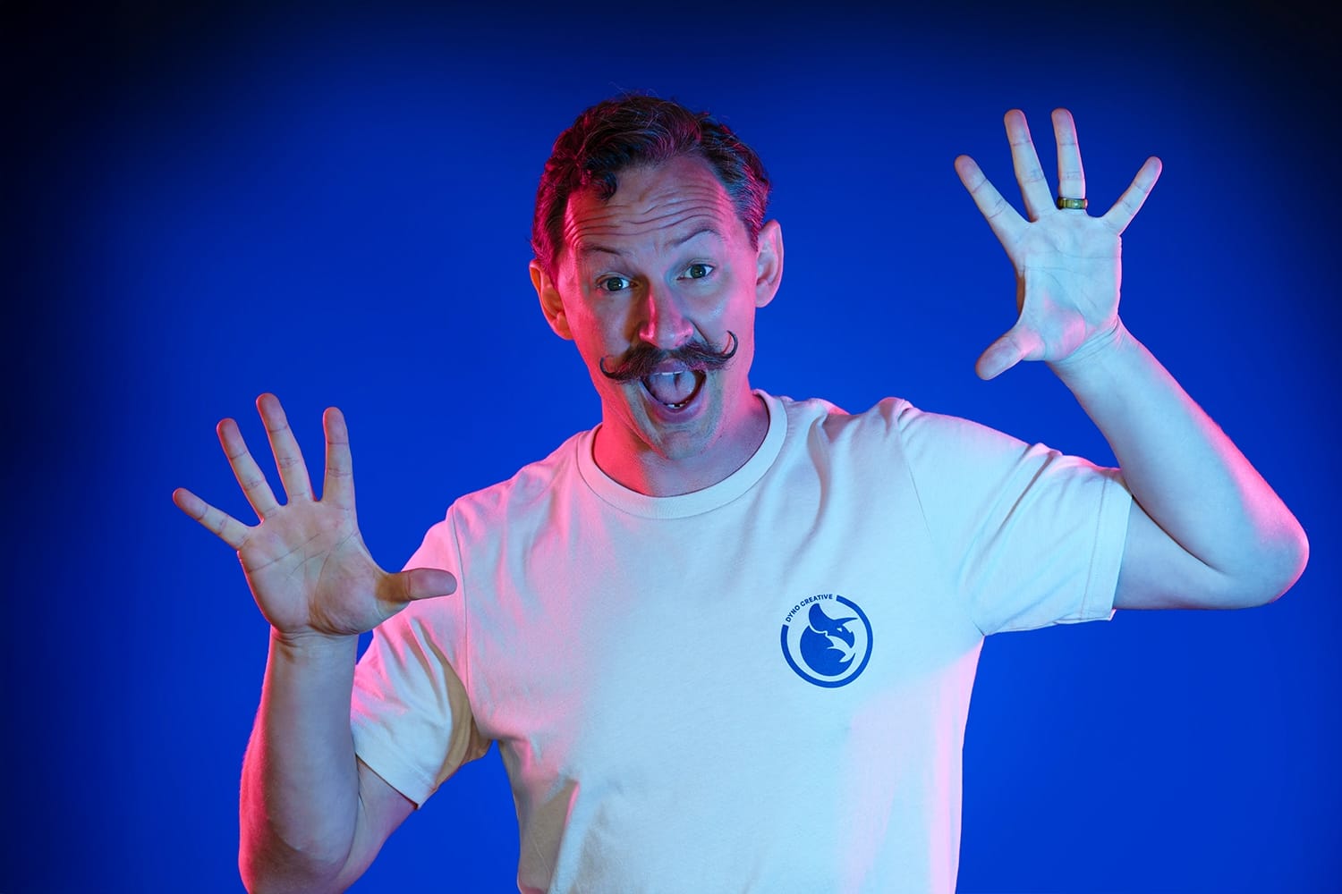 Cheerful person with mustache, blue and pink lights.